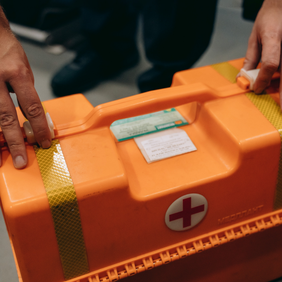 Hands touching a bright orange first aid box
