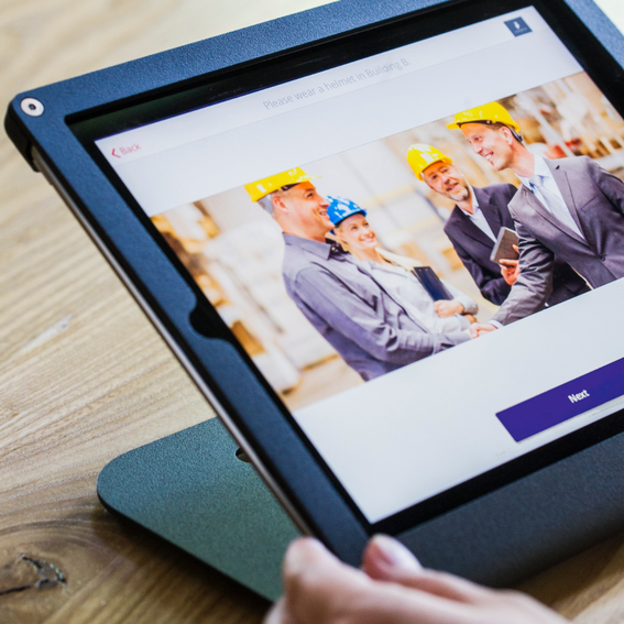 A tablet device with an image of three men and a woman in yellow and blue hard hats