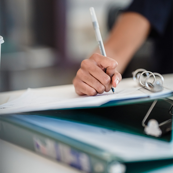 Woman's hand holds pen above binder