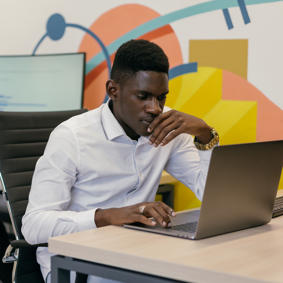 Man in white shirt sits at table with laptop