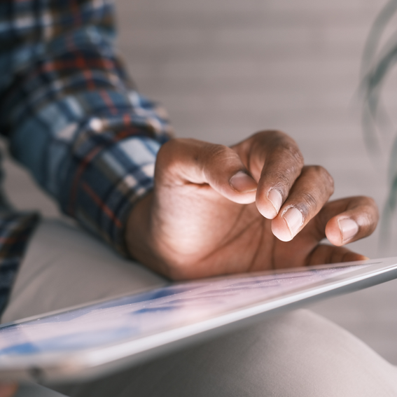 A man in a checkered shirt holding a grey tablet device