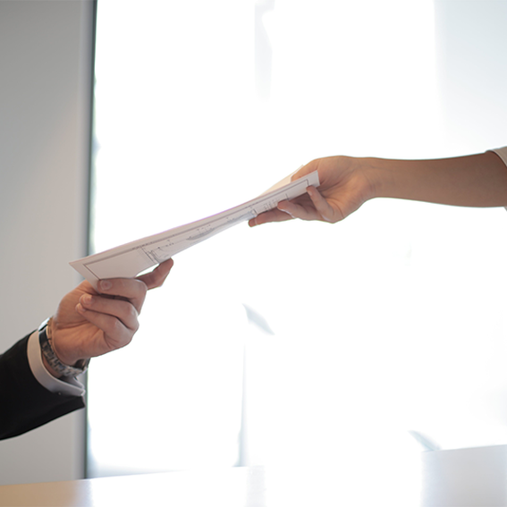 man in black suit hands woman in white shirt a piece of paper