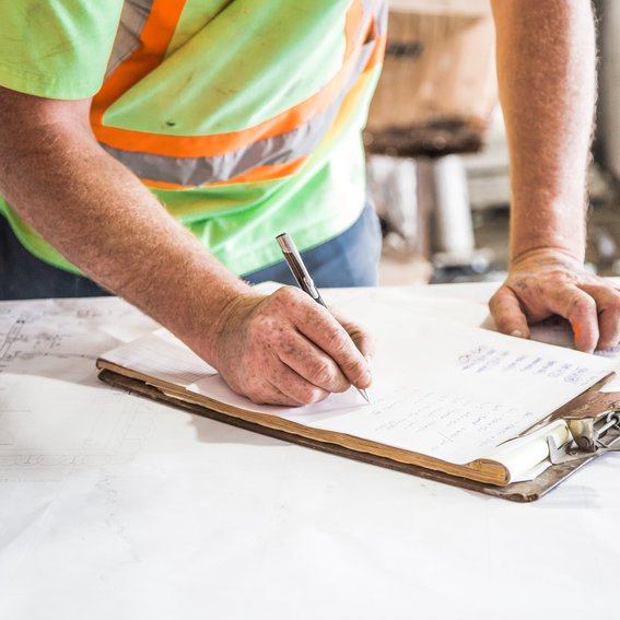 man in green hi-vis jacket writing on a clipboard