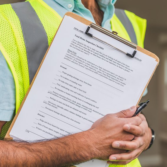 Man in short-sleeved green hi-vis jacket holds a clipboard